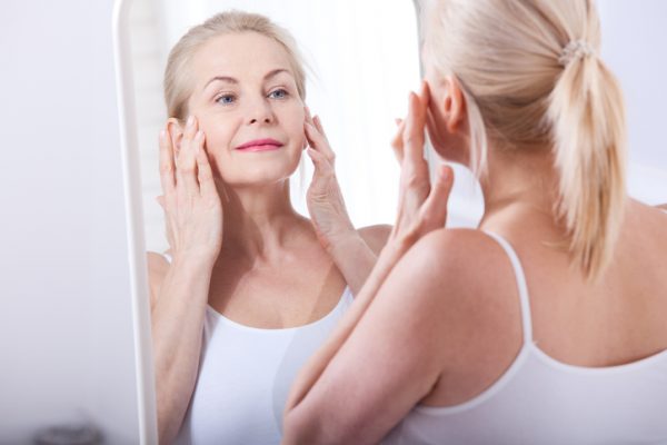 aging hair blonde woman looking in mirror wrinkles mature viviscal hair blog
