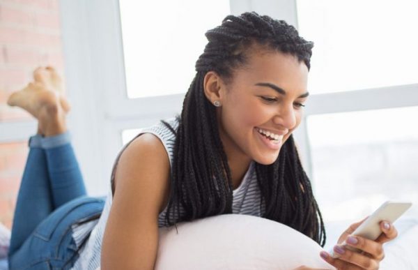 kvinna ler mot telefonen virka box flätor tips för att använda flätförlängningar viviscal hår blogg