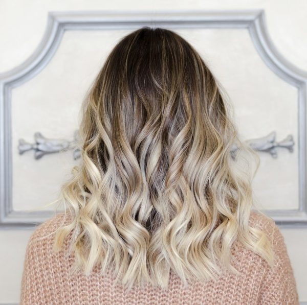 Back view of a woman’s hair. It is curly, ombre hair that goes from dark brown to ice blonde. Balayage vs Ombre, What’s the Difference?
