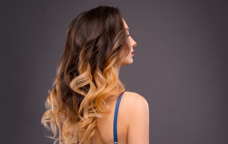 Side view of a woman with long, curly, ombre hair. Balayage vs Ombre, What’s the Difference?