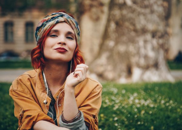 Woman showcases a boho headband in her bright red hair as she sits outside 