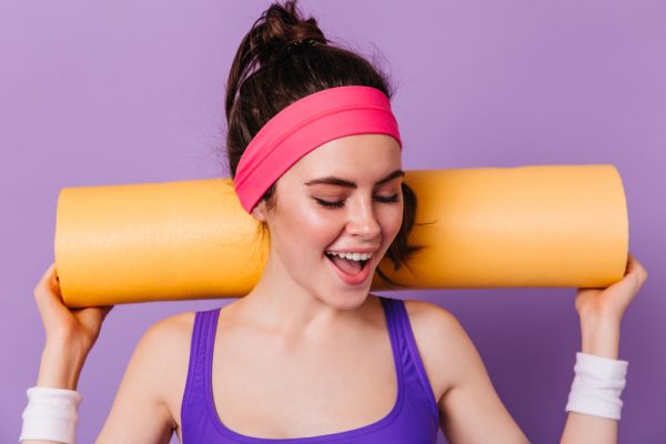 Woman has her hair pulled into a ponytail, and a workout headband keeping the sweat from her eyes as she prepares for the gym