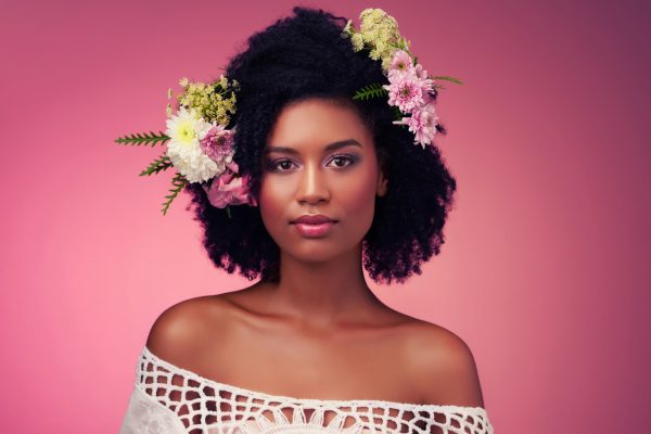 kvinna afrikansk amerikan naturligt hår lockigt kort rosa bakgrund vit off the shoulder blommor i naturlig textur hår vår hår trend hår blommor viviscal hår blogg