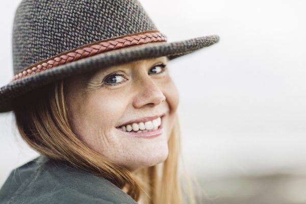 närbild leende rödhårig kvinna hatt vad ditt hår säger om dig viviscal hår blogg