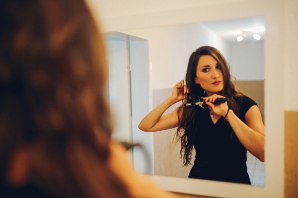 kvinna brunt hår styling hår platt järn spegel badrum vad ditt hår säger om dig viviscal hår blogg
