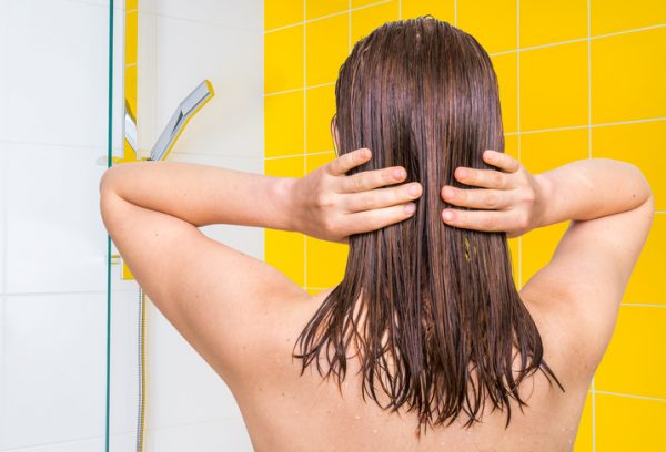 Attraktiv kvinna applicerar balsam på håret