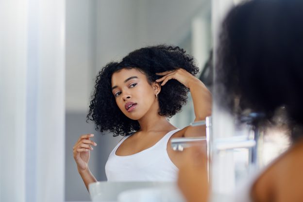 Woman styling her hair in bathroom mirror